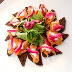 smoked salmon on pumpernickel toasts with crème fraiche and pickled onion